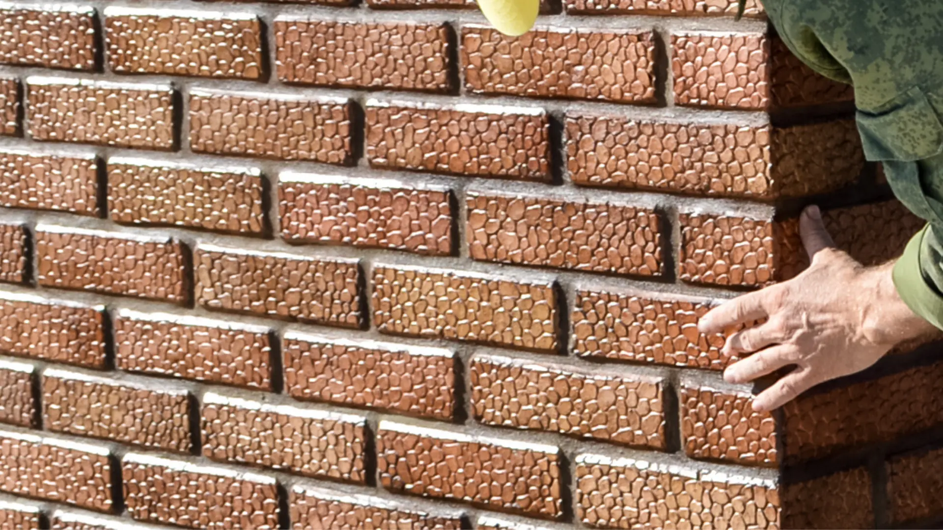Bricklayer checking completed facing brickwork and mortar joints at final handover inspection