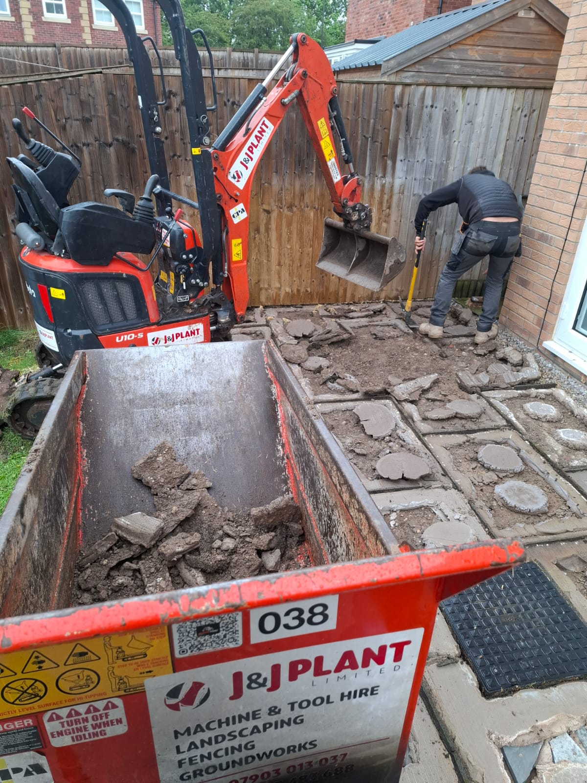 Mini excavator breaking out an existing paved area at the start of a driveway and groundworks job
