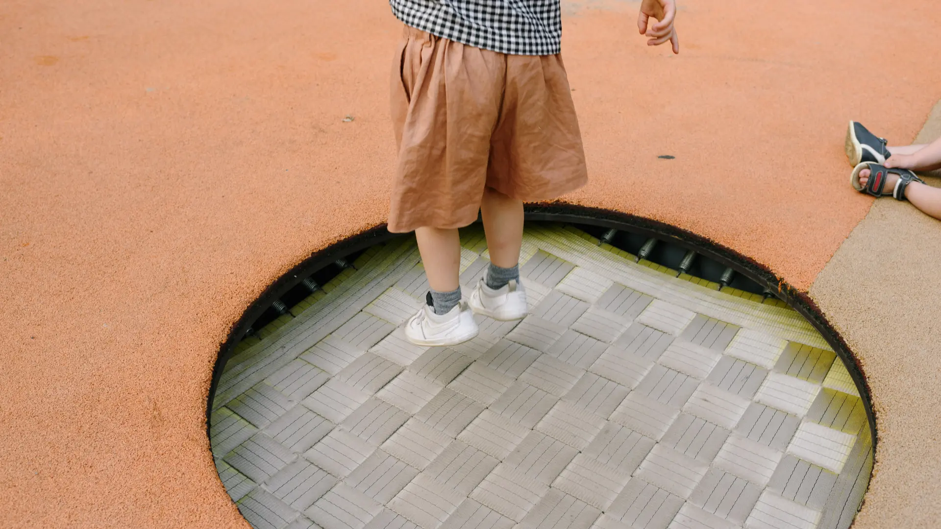 Sunken trampoline installed flush with a safety surface in a family garden