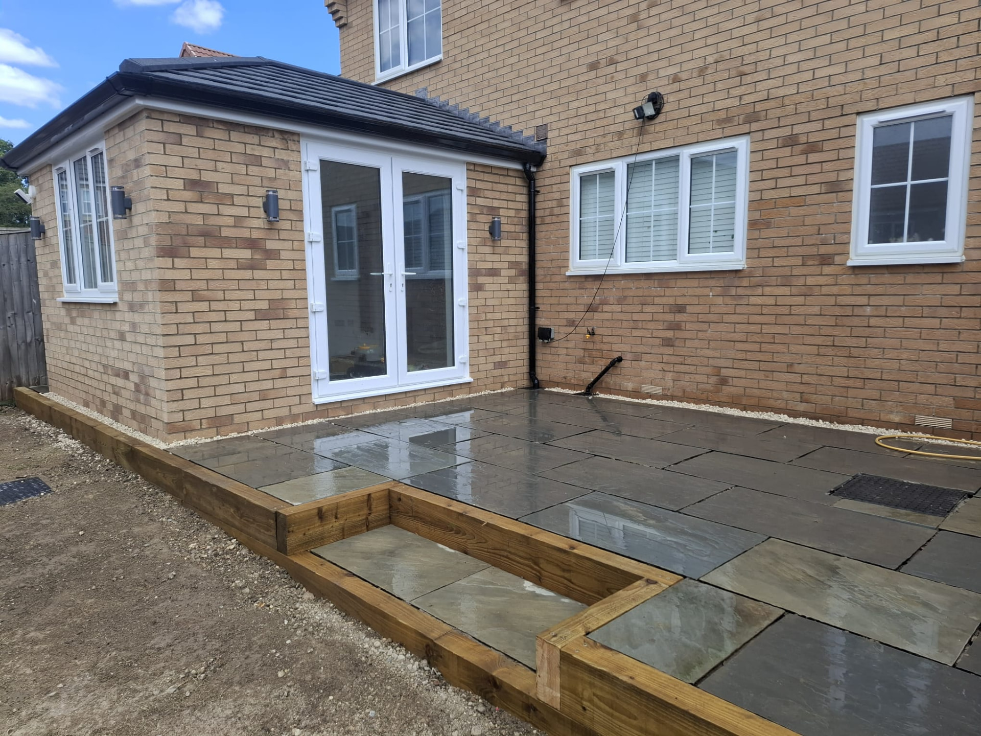 Completed Indian sandstone patio with timber sleeper edging laid to falls behind a Doncaster home