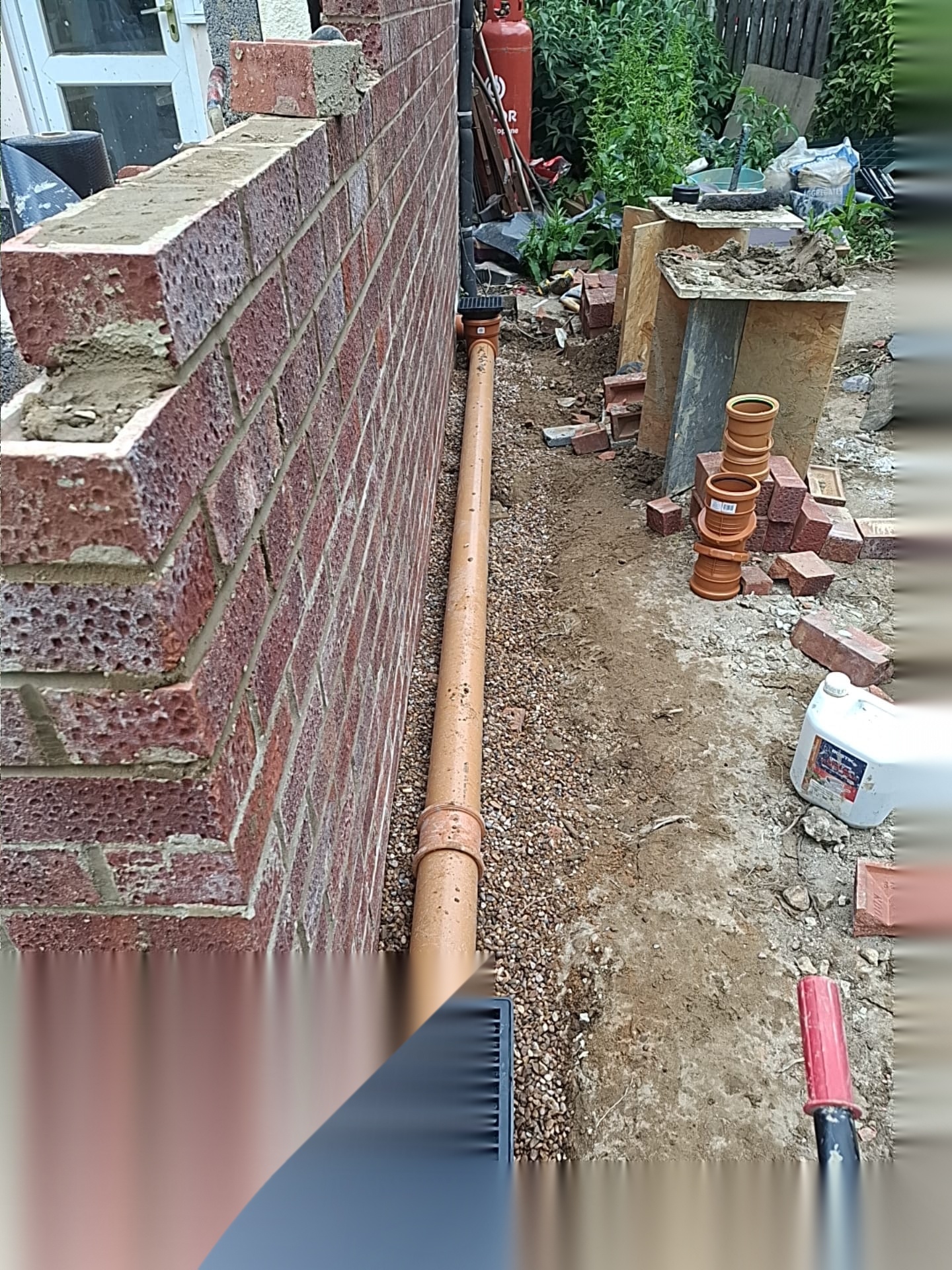 New drainage pipework laid alongside a part-built brick wall during groundworks in Doncaster