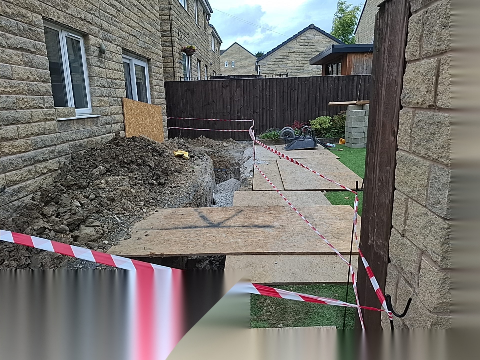 Excavated trench with a temporary boarded walkway maintaining safe access during groundworks