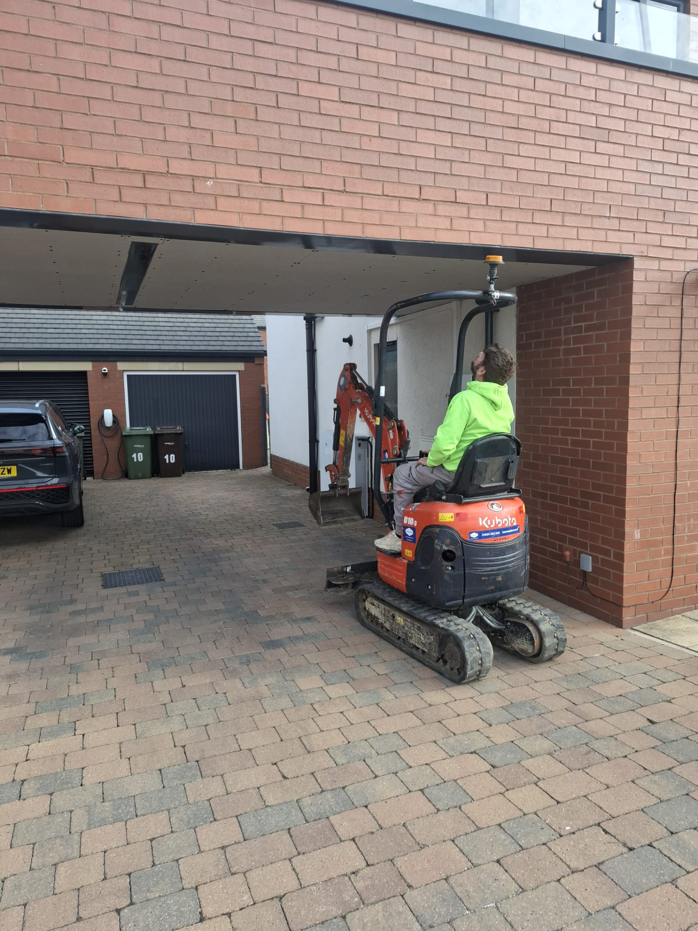 Mini excavator working in a restricted access area beneath a carport during residential groundworks