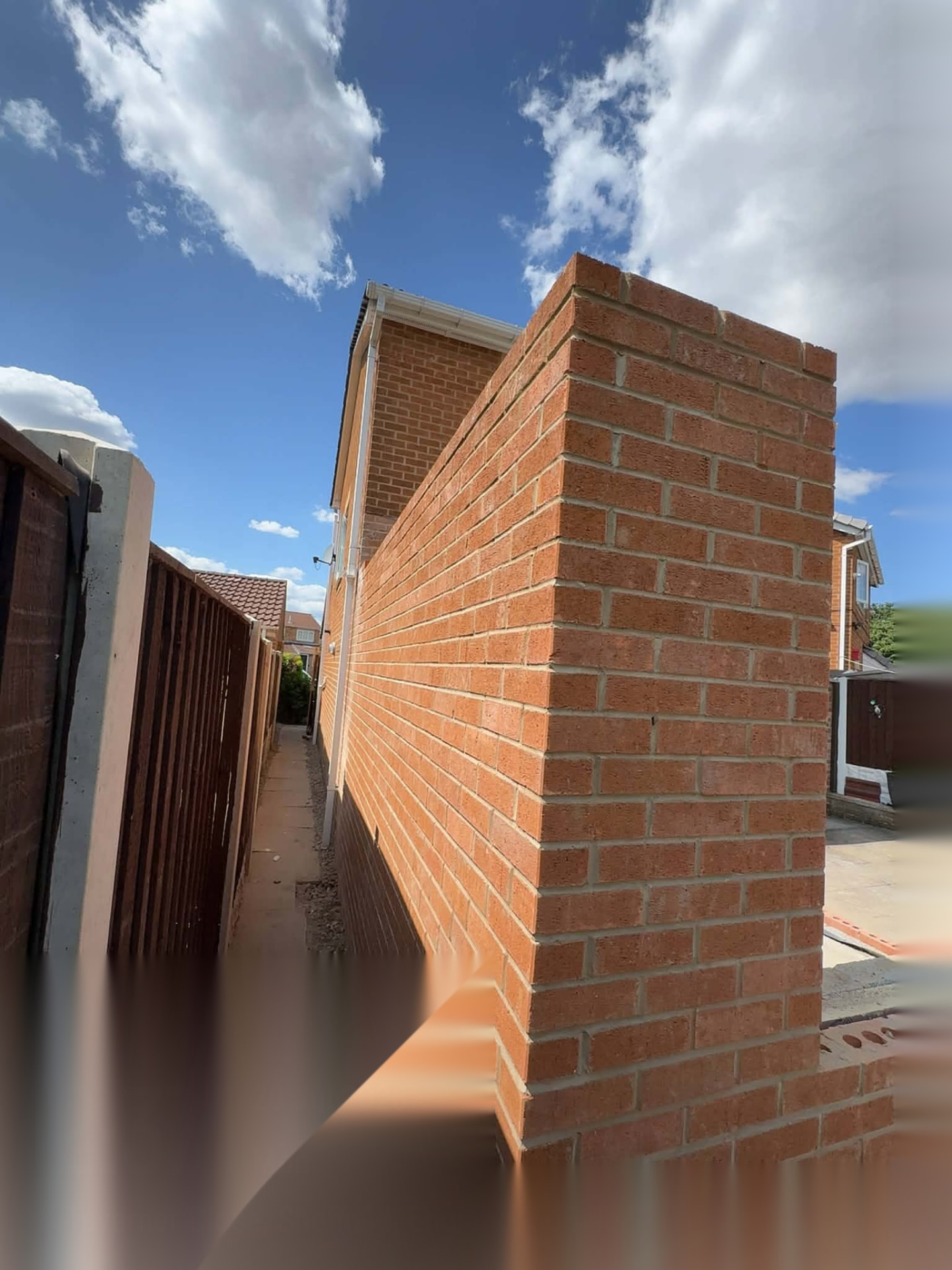 Tall red brick boundary wall built straight and true against a clear sky by a Doncaster bricklayer
