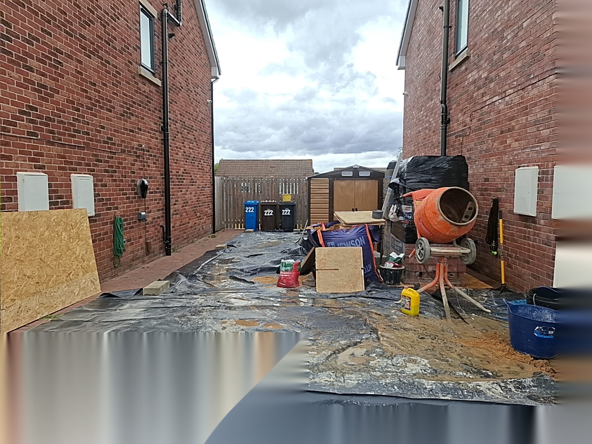Protected residential courtyard set up with mixer and materials during groundworks
