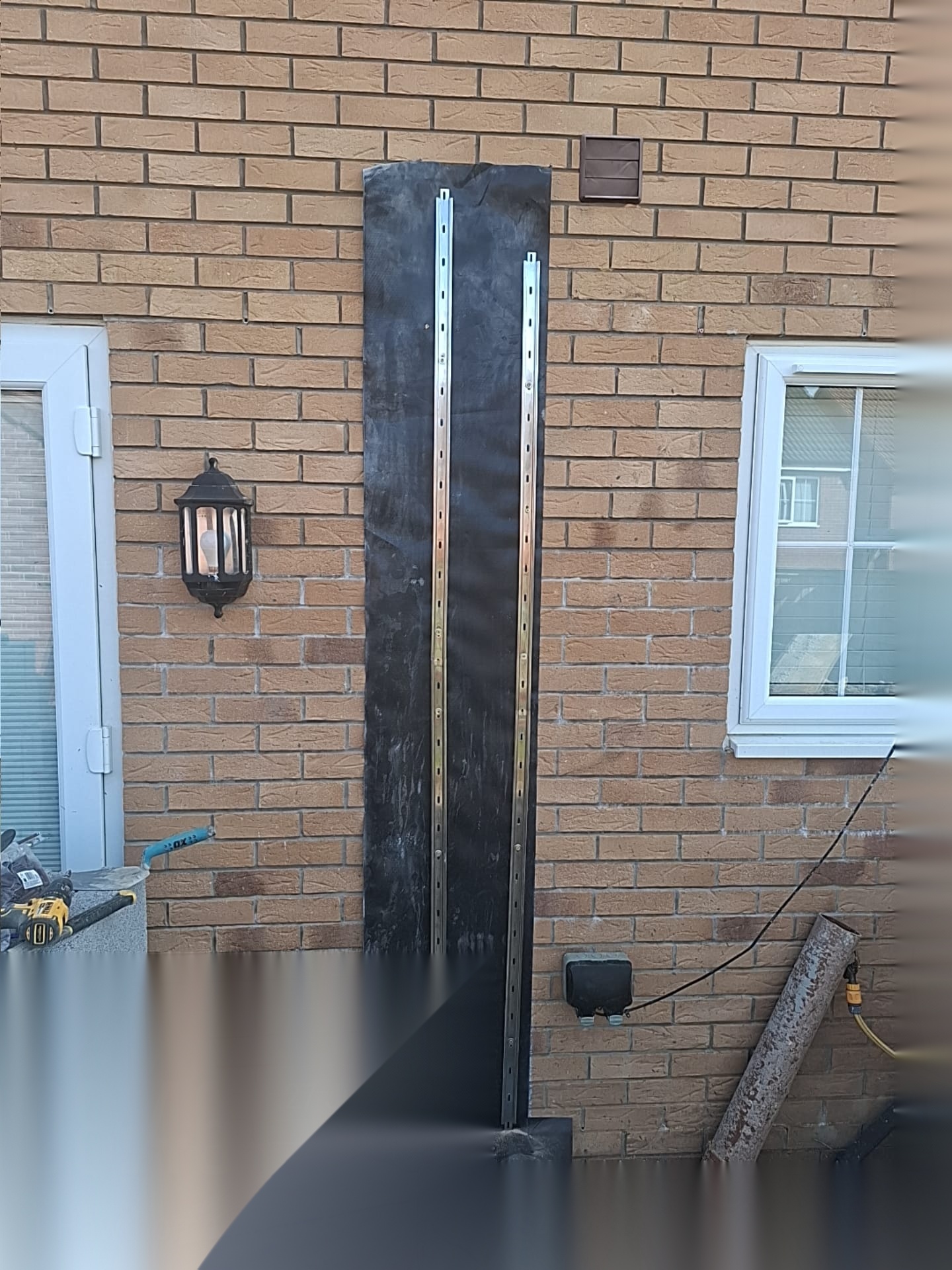 Temporary support and flashing detail fixed to a brick facade between new openings during extension works