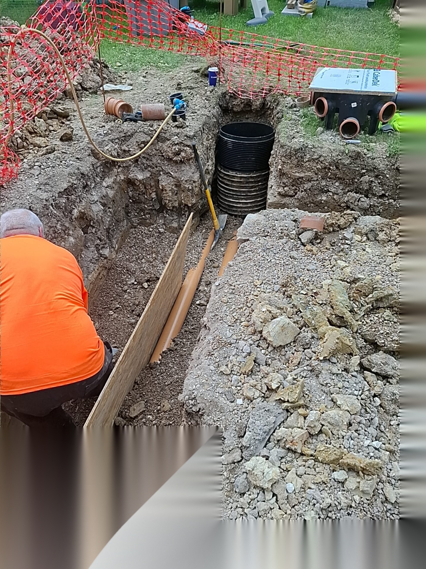 Drainage installation with a new inspection chamber and pipework inside a fenced excavation