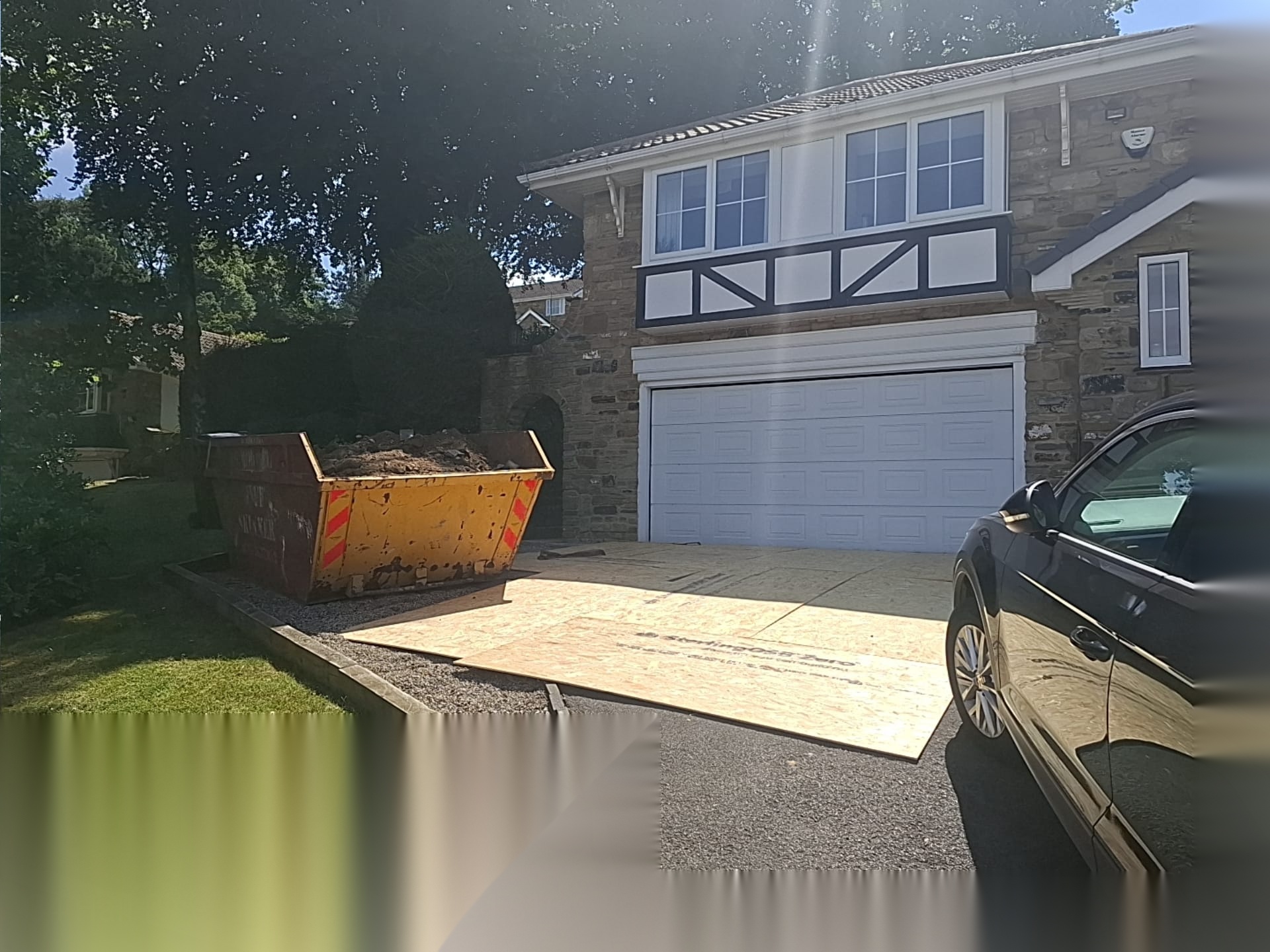 Driveway protected with boards and a skip positioned for tidy muck away during works