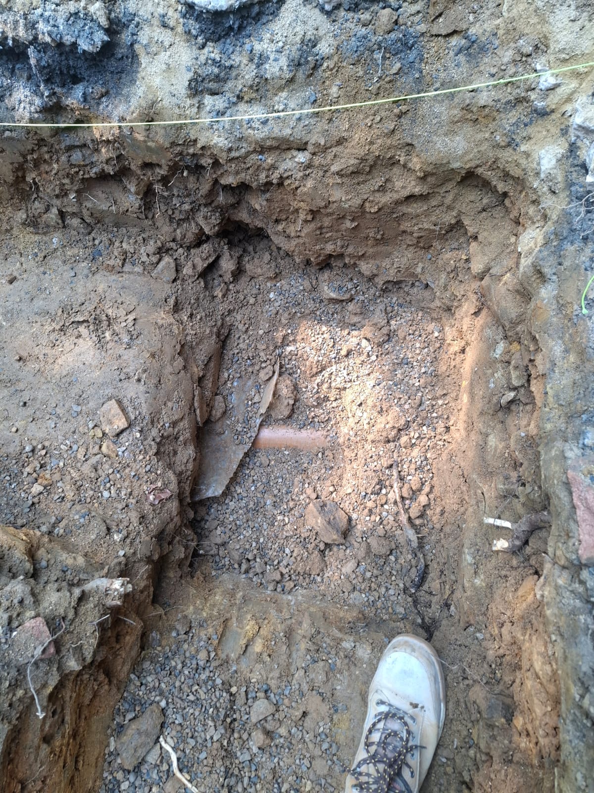 Soil profile and existing underground pipe exposed in a trench during groundworks inspection