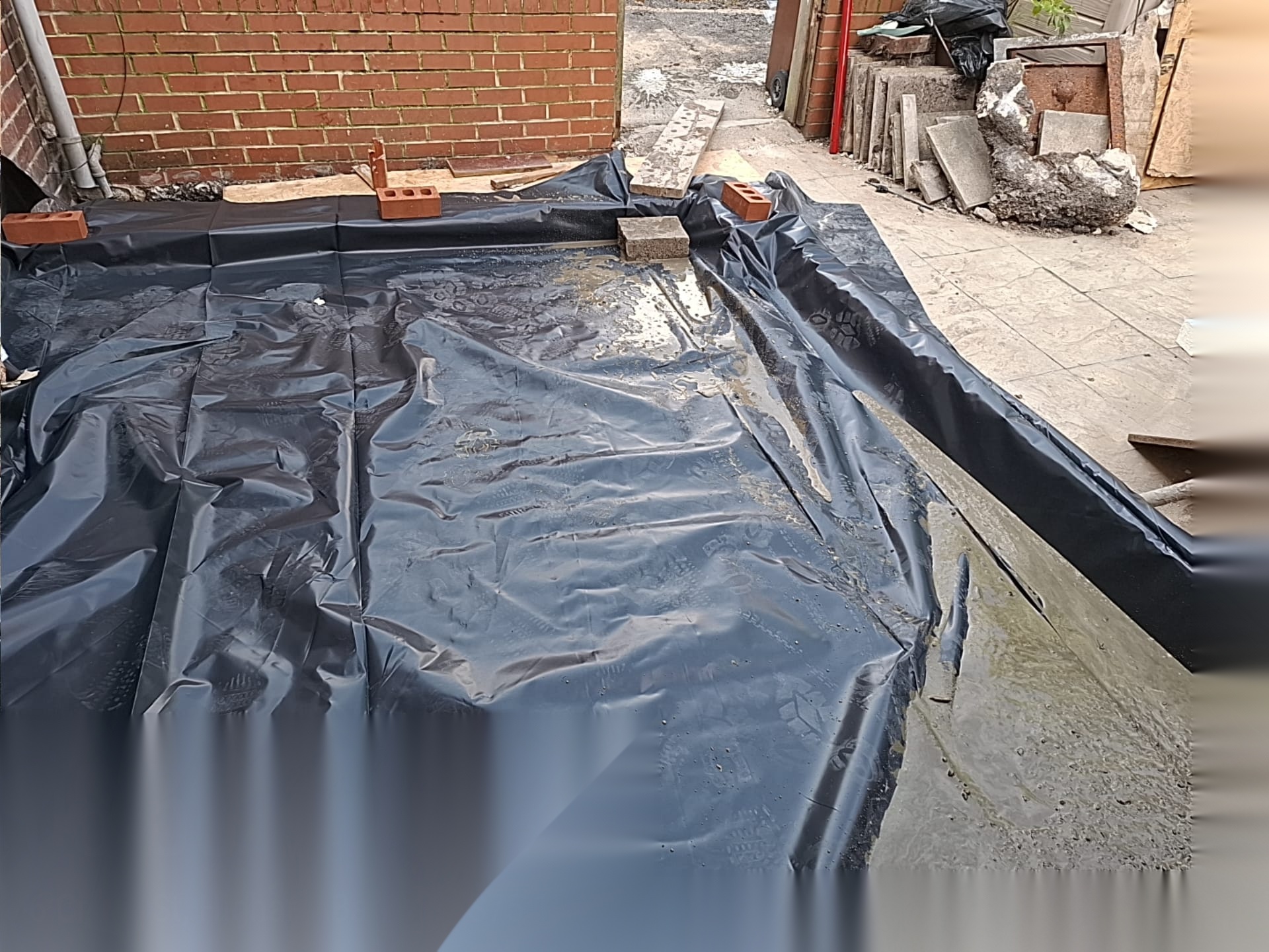 Membrane laid over a prepared base with bricks and materials set out ready for building