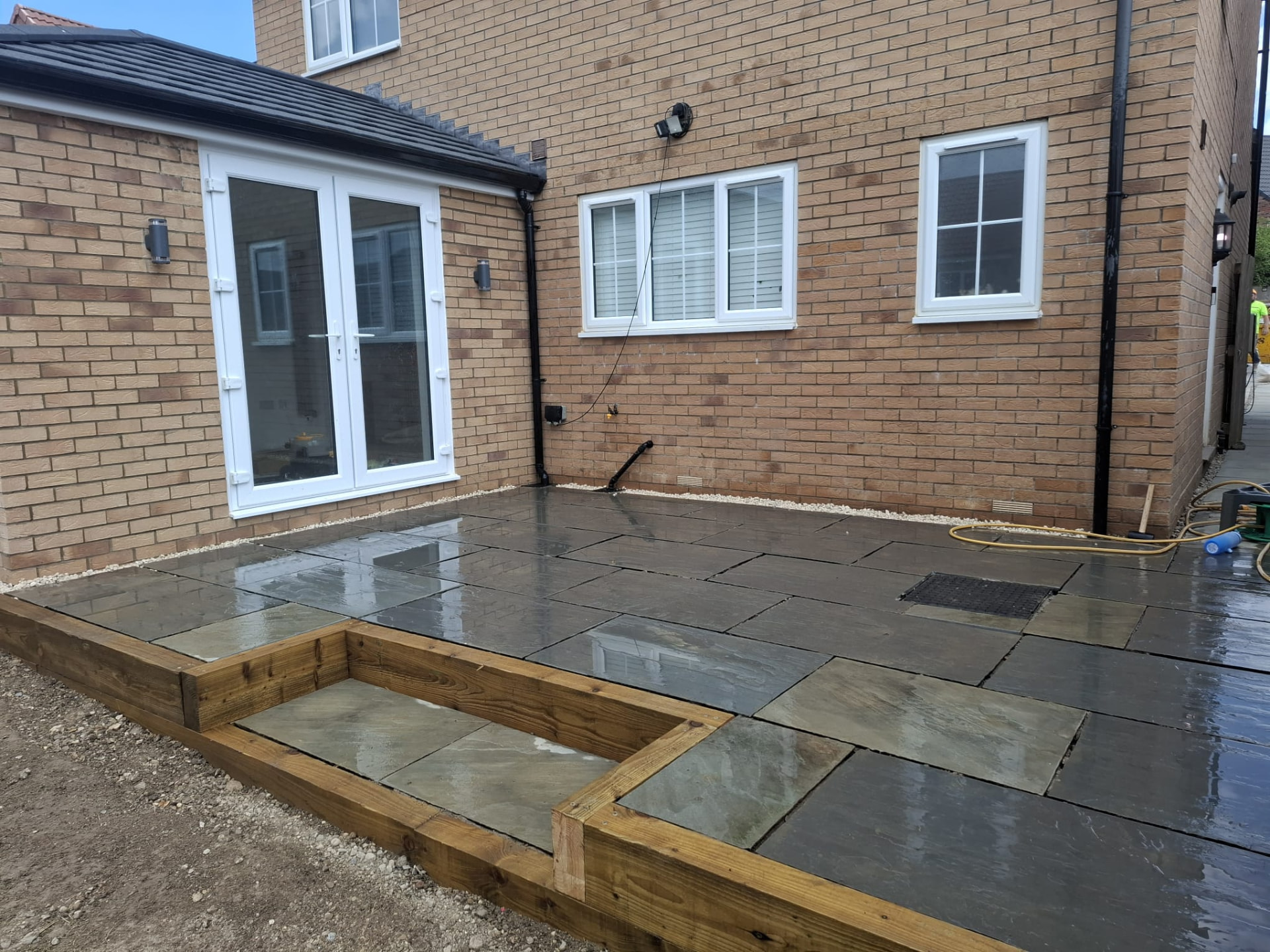 Completed rear garden patio in natural stone with sleeper edging and gravel margin to the house