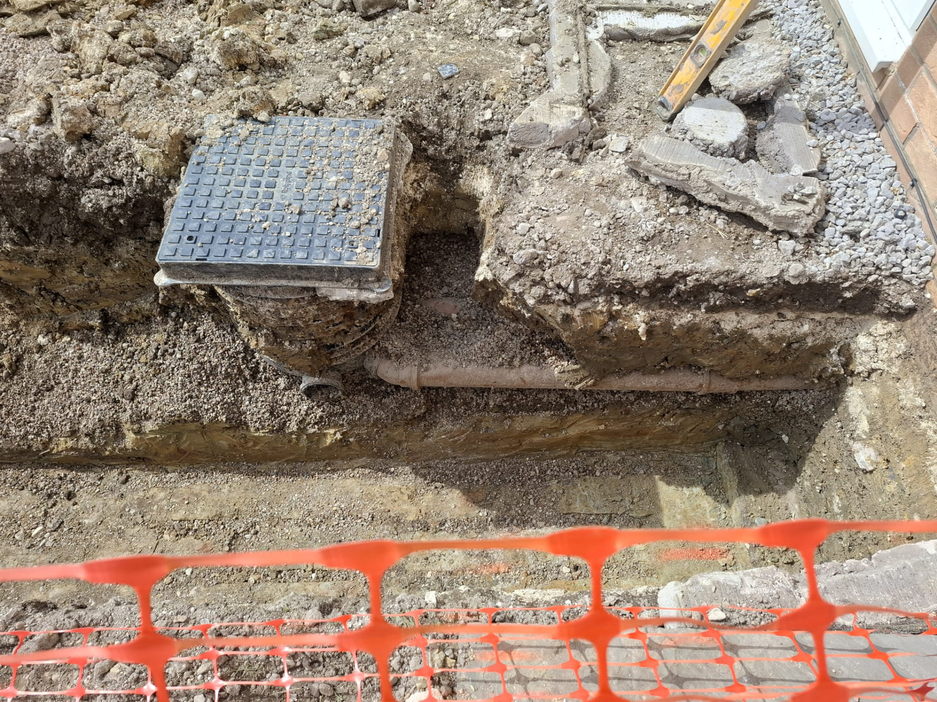 Drainage inspection chamber and pipework exposed in an excavation during South Yorkshire groundworks
