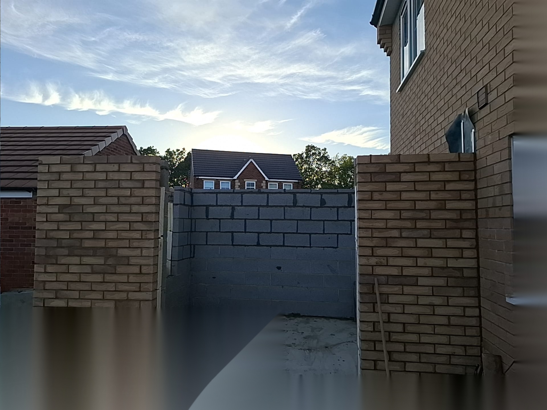 Blockwork wall being raised between finished brick piers on a residential brickwork job in Doncaster